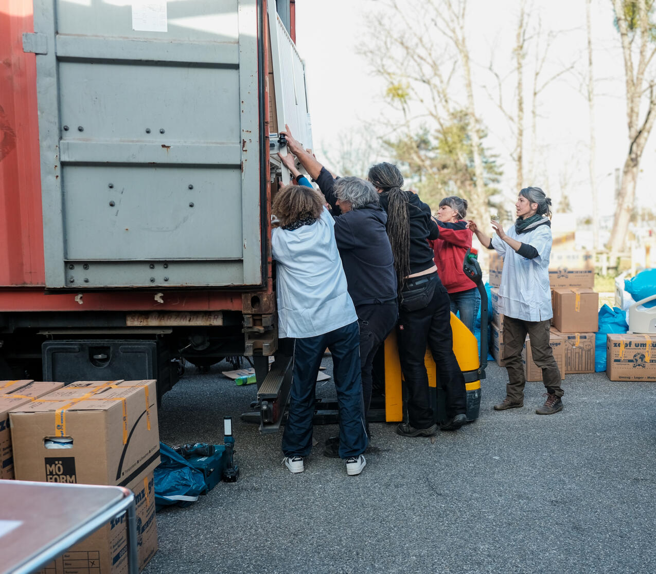 Viele Menschen beim Beladen eines Seecontainers