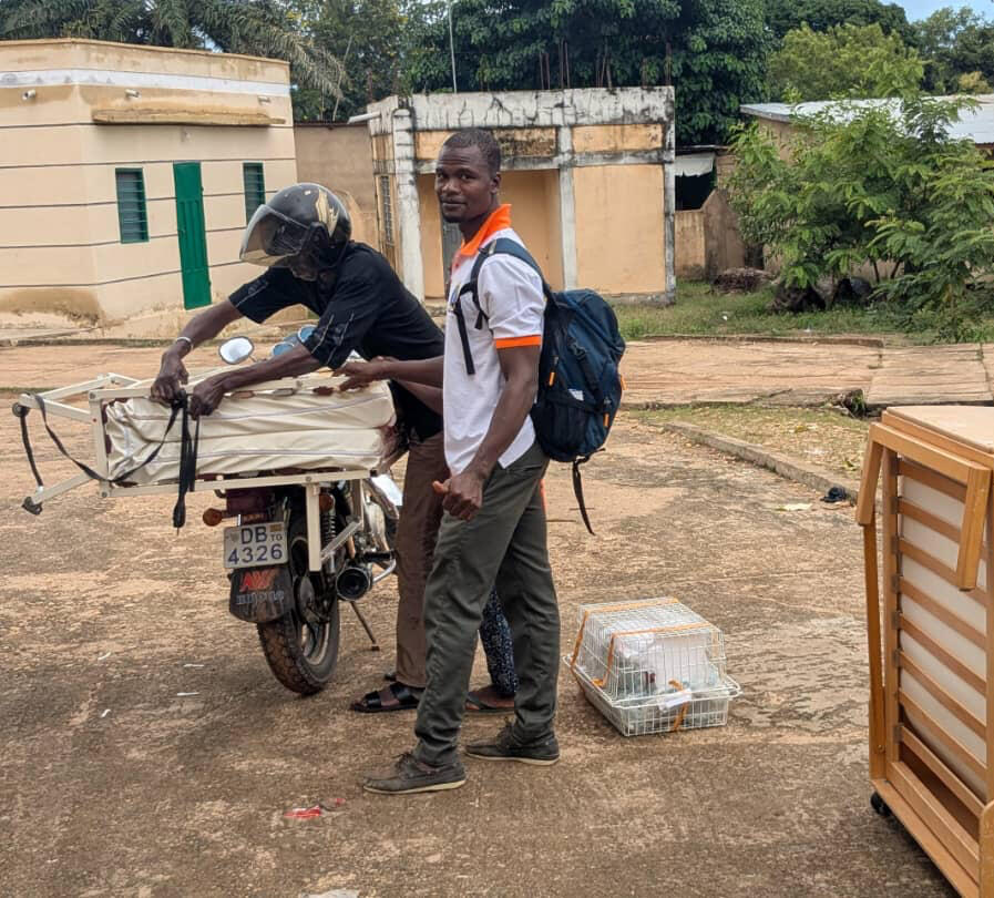 Ein Mann lädt ein Krankenhausbett auf sein Moped und sichert es.