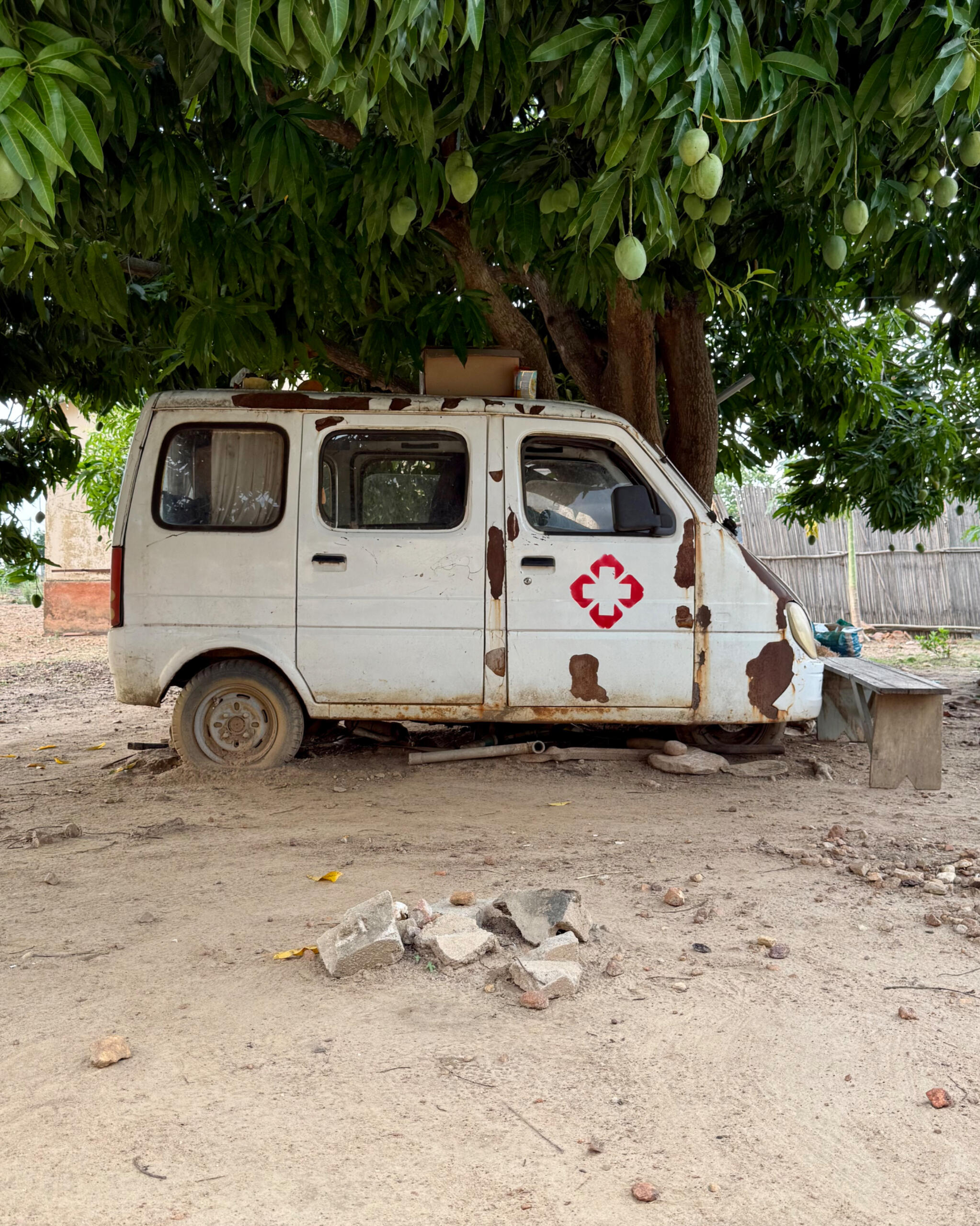 Krankentransporter, der verrostet und kaputt vor einem Mangobaum steht